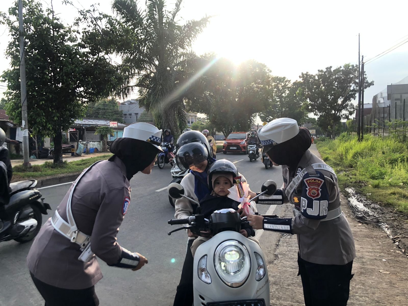 personel membagikan cokelat dan permen kepada anak-anak sekolah di titik pengaturan lalu lintas